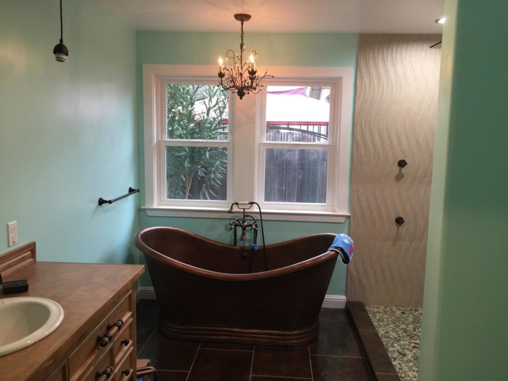Bathroom with aqua walls, freestanding bronze tub, counter and open shower